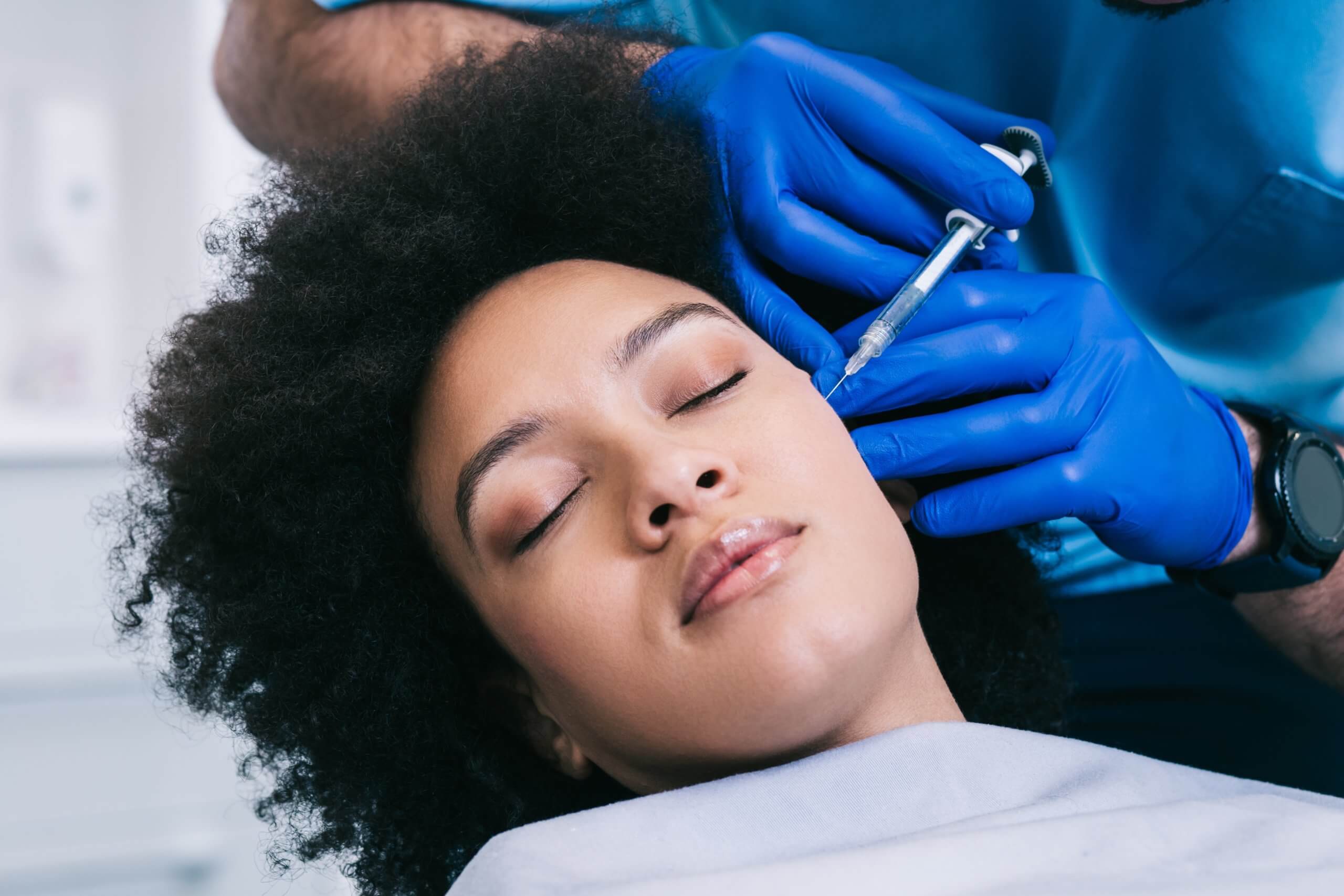 Doctor cosmetologist making injection with filler in mature woman patient cheek on face to moisturize and rejuvenate skin, side view. Beauty cosmetic procedure against wrinkle in clinic | Resa Medical Aesthetics in Scottsdale, AZ